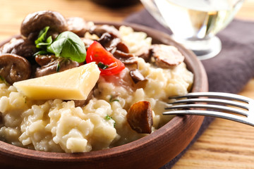 Bowl with risotto and mushrooms on wooden table, closeup
