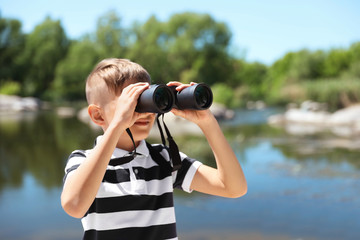 Fototapeta na wymiar Little boy with binoculars outdoors. Summer camp