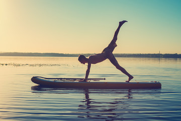 Silhouette of man practicing yoga on a SUP