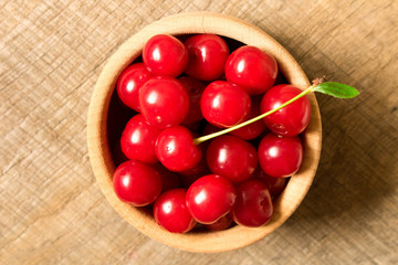 Ripe red cherry in a wooden plate on an old wooden table. The concept of natural food