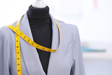 Mannequin with jacket and measuring tape in tailor studio, closeup