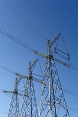 three power line pylons against a blue sky background. .