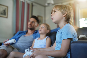 Daddy with kids playing video game at home