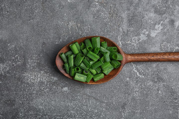 Fototapeta na wymiar Spoon with chopped green onion on table, top view