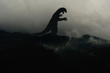Fototapeta premium Silhouette eines Godzilla-artigen Monsters im Nebel auf einem Berg