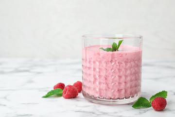 Delicious smoothie with raspberries in glass on marble table