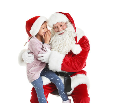 Little girl whispering in authentic Santa Claus' ear against white background