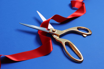 Ribbon and scissors on color background. Ceremonial red tape cutting