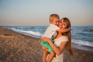 Naklejka premium Happy mother and son hugging at beach