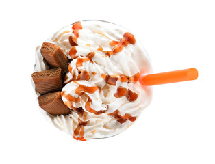 Glass of delicious milk shake with whipped cream and caramel candies on white background, top view