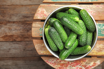 Bowl with ripe fresh cucumbers on table, top view