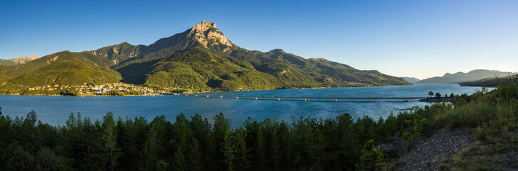 Fototapeta premium Sunset on Grand Morgon peak, Savines-le-Lac village and Serre-Poncon Lake (panoramic). Hautes-Alpes, European Alps, France