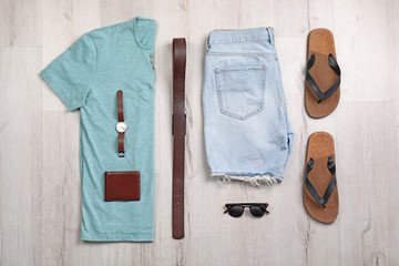 Set of stylish clothes and accessories on wooden floor, flat lay