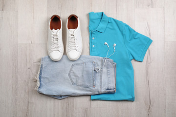 Set of stylish clothes and accessories on wooden floor, flat lay