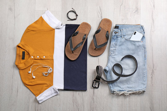 Set of stylish clothes and accessories on wooden floor, flat lay