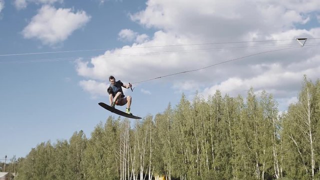 Wakeboarder sport handsome man on wakeboard doing extreme tricks ollie 180 360 Jump from trampline kicker, water sportsman male on board