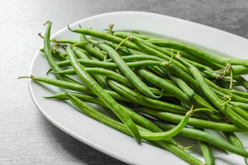 Plate with fresh green French beans on table, closeup