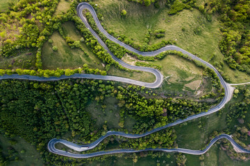 Winding road from high mountain pass, in summer time. Aerial view by drone . Romania	
