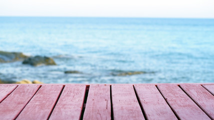 Fototapeta na wymiar The blur cool sea background with wood floor foreground on horizon tropical sandy beach; relaxing outdoors vacation with heavenly mind view at a resort deck touching sunshine
