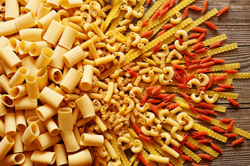 Yellow and red italian pasta on a wooden background