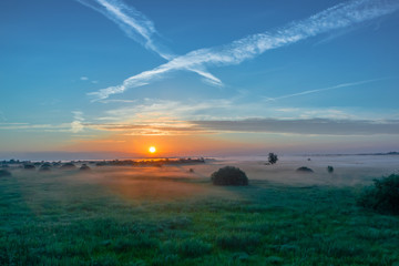 Natural Park of Biebrza Valley - sunrise in foggy morning over medow and pool