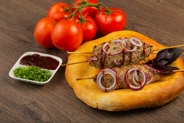 Lulya-kebab. Shish kebab on a stick, minced meat. Traditional Caucasian dish. On a cutting board, with green salad, ketchup, spices