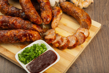 Homemade sausage on a wooden background with seasonings and sauce.