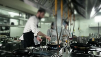 Chef is making flambe sauce on restaurant kitchen with onion and wine