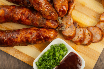 Homemade sausage on a wooden background with seasonings and sauce.