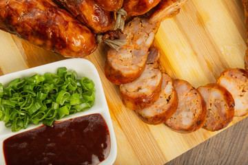 Homemade sausage on a wooden background with seasonings and sauce.