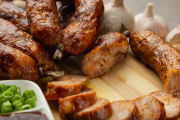Homemade sausage on a wooden background with seasonings and sauce.