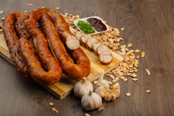 Homemade sausage on a wooden background with seasonings and sauce.