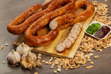 Homemade sausage on a wooden background with seasonings and sauce.