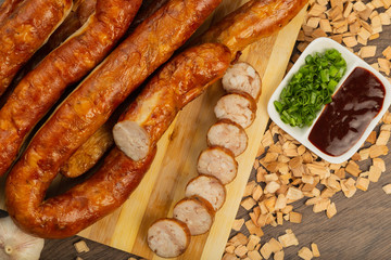 Homemade sausage on a wooden background with seasonings and sauce.