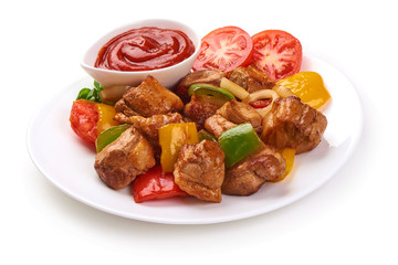 Pieces of grilled barbecue with vegetables and tomato sauce on plate, isolated on white background. Close-up