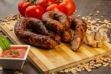 Homemade sausage on a wooden background with seasonings and sauce.