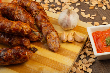 Homemade sausage on a wooden background with seasonings and sauce.