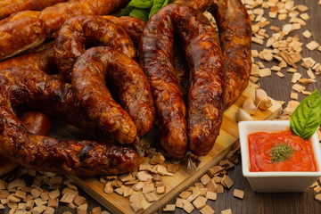 Homemade sausage on a wooden background with seasonings and sauce.