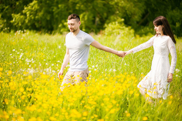 Couple walking in the yellow meadow holding by hands
