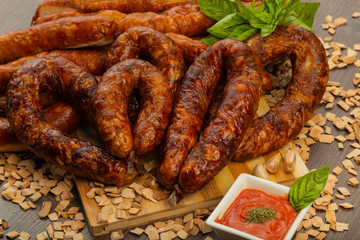 Homemade sausage on a wooden background with seasonings and sauce.
