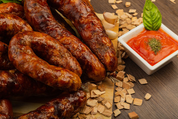 Homemade sausage on a wooden background with seasonings and sauce.