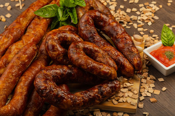 Homemade sausage on a wooden background with seasonings and sauce.