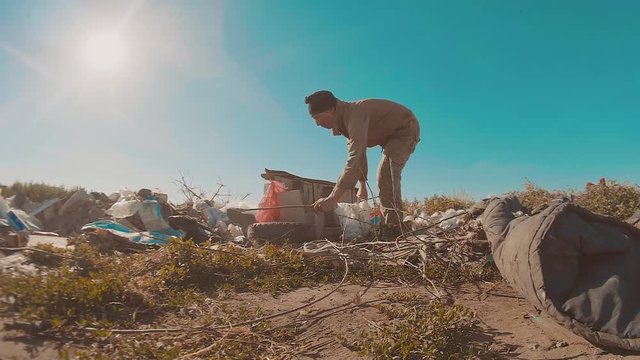 dirty homeless man at the dump lifestyle slow motion video. homeless roofless person looking for food in a dump. refugee homeless illegal immigration poverty concept