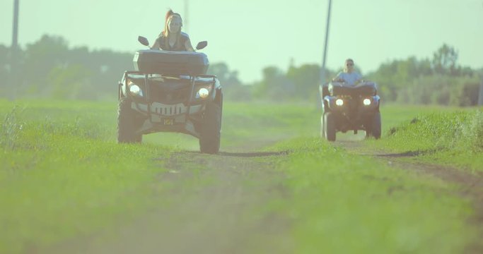 Girls riding on extreme quadrocycle ATV in a field off-road