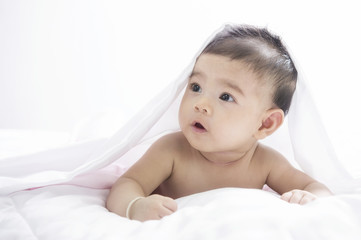 Smiling baby girl lying on a bed
