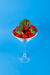 Martini glass filled with veggies on solid blue background