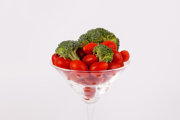 Fototapeta na wymiar Close up vegetables in a martini class broccoli cherry tomatoes on solid background