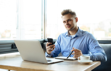 Young man drawing template for the web site associated with digital marketing, current trends and tendencies of UX / UI design. Businessman who rules his company remotely, like a freelancer