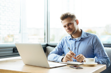 Young man drawing template for the web site associated with digital marketing, current trends and tendencies of UX / UI design. Businessman who rules his company remotely, like a freelancer