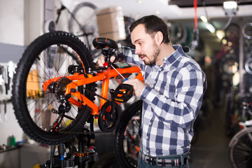 Fototapeta na wymiar Man in sports workshop mounts bike using special tools
